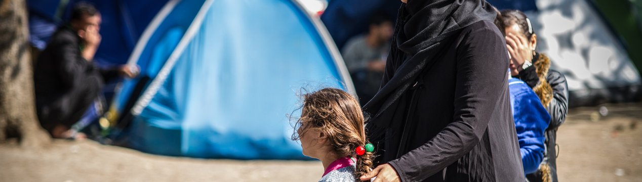 Mutter und Töchter vor Flüchtlingszelten
