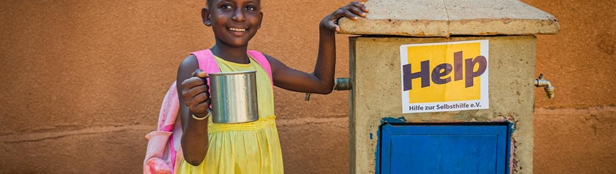 Ein malisches Mädchen steht neben einem von Help errichteten Brunnen