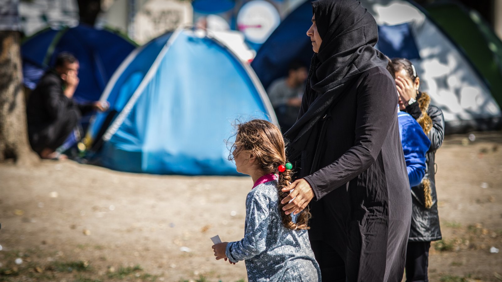 Mutter und Töchter vor Flüchtlingszelten