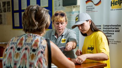 Eine Ukrainerin wird von zwei Help-Mitarbeiterinnen für Hilfsmaßnahmen registriert