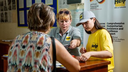 Eine Ukrainerin wird von zwei Help-Mitarbeiterinnen für Hilfsmaßnahmen registriert