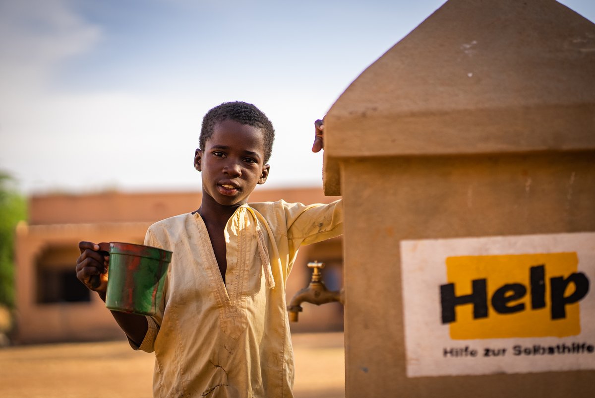 Ein Junge steht neben einem Help-Brunnen in Mali